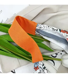 Détail de la poignée en sangle orange renforcée et imprimé fleuri du grand sac cabas