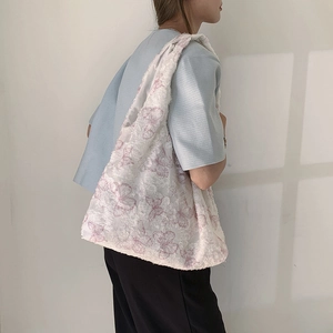 White textured fleece tote bag with pink butterfly prints shown on a model's shoulder