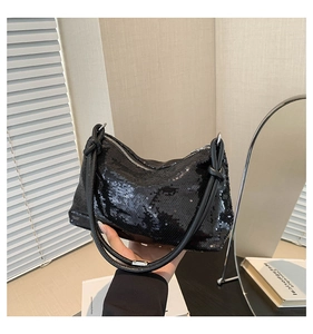 Detail of black sequined handbag with shimmering texture and decorative knot handle