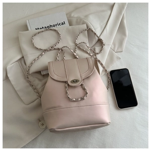 Dettaglio borsa in pelle rosa cipria con chiusura a rotazione su blazer beige