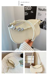 Detail of off-white leather shoulder bag with silver heart charm and pearl chain accent