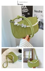 Detail of pea green pleated handbag with decorative pearl and silver heart chain strap