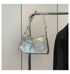 Macro shot of silver sequin shoulder bag featuring knotted strap and metallic texture
