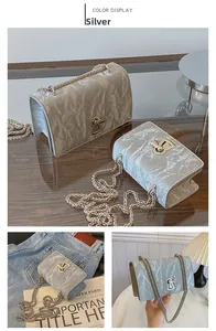 Detail of silver textured crossbody bag featuring metallic chain and unique twist lock