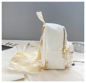 Detail des weißen Paillettenrucksacks mit goldenen Reißverschlüssen und Blumenstickerei