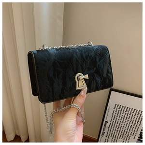 Detail of black crossbody bag with pleated texture and silver keyhole lock mechanism
