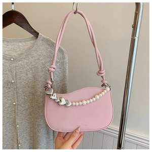 Detail of pink shoulder bag with heart charm, pearl chain and wavy top edge design