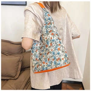 Détail du sac cabas floral avec sangle orange et motif fleuri bleu porté à l'épaule
