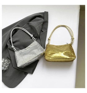 Detail of sequined shoulder bag with knot handle next to a grey blazer on white background