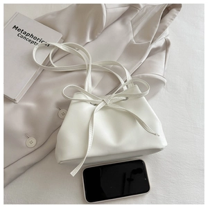 Detail of white PU leather bucket bag with bow and smartphone for size reference