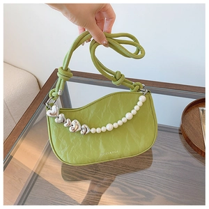 Close-up of avocado green pleated bag with silver heart and pearl chain detail