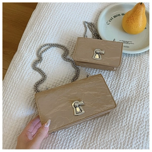 Detail view of glossy wrinkled beige shoulder bags in two sizes with silver chain and lock