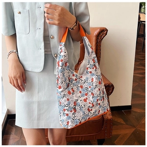 Détail du sac cabas en toile à fleurs avec anses orange et motifs floraux rouges