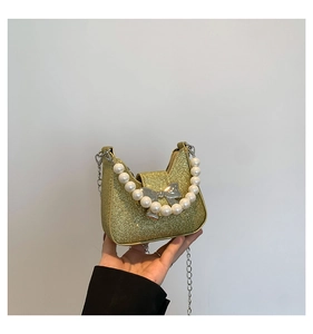 Detailed macro of gold glitter mini bag with silver bow and large pearl chain handle
