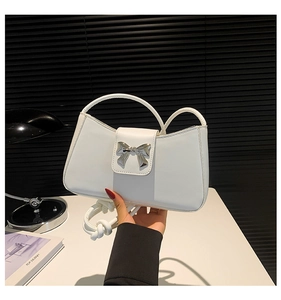 Close-up of a white rectangular shoulder bag featuring a polished silver bow buckle detail