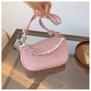 Close-up of pink crescent bag featuring heart-shaped metal links and pearl chain details