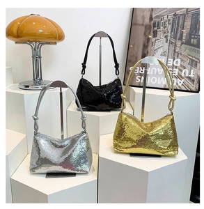 Three sequined crescent underarm bags in gold silver and black on geometric pedestals