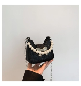 Macro view of black sequined handbag featuring a silver bow and large pearl handle