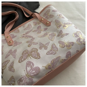 Close-up of jacquard tote bag with butterfly patterns and pink leather trim details
