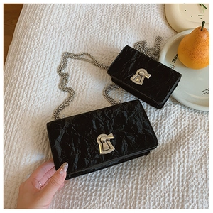 Detail view of two black pleated leather handbags with silver metallic irregular twist locks