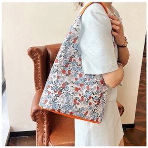Vue détaillée du sac cabas floral avec passepoil orange vif et texture du tissu fleuri