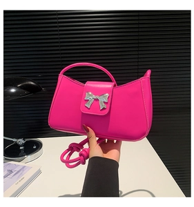 Detail of silver bow clasp on magenta leather handbag with premium smooth finish