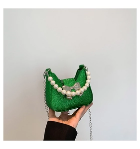Detail of green glitter fabric handbag with pearl handle and silver bow clasp
