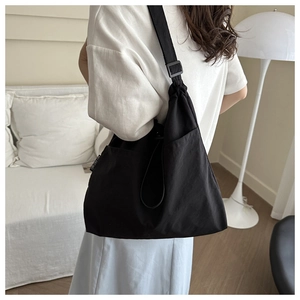 Detailed view of black canvas crossbody bag featuring adjustable straps and side pockets