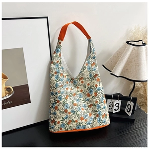 Sac cabas en toile à fleurs sur table en bois avec anses orange vif et détails style hobo