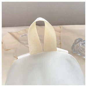 Makrodetail des oberen Nylon-Tragegriffs am cremeweißen Reise-Rucksack