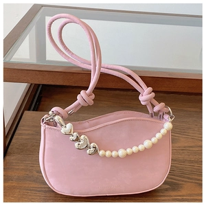 Close-up of pink crescent bag with heart-shaped metal chain and pearl handle detail