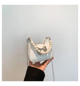 Detail of white sequin handbag with pearl handle, metal bow, and silver chain strap
