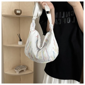 Detail of white wrinkled nylon crescent bag with colorful embroidered stitching and wide strap