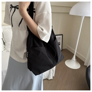 Detail of a large black canvas tote bag with side pocket shown in a lifestyle setting
