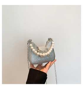 Macro detail of silver glitter mini bag featuring a pearl handle and chic bow decoration
