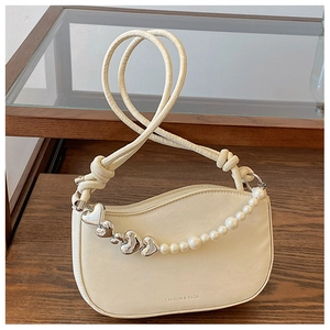 Detail of cream crescent bag with silver heart charm and pearl chain decoration