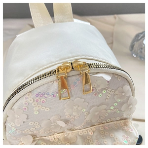 Nahaufnahme der 3D-Blumenapplikationen und Pailletten auf einem weißen Mini-Rucksack