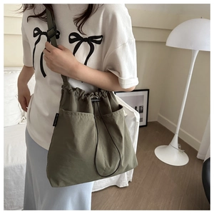 Detail of adjustable shoulder strap and drawstring closure on olive green canvas bag