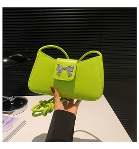 Detail of lime green leather handbag with silver butterfly clasp and woven handle