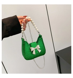 Detail of green sequin mini bag with silver bow accent and white pearl top handle