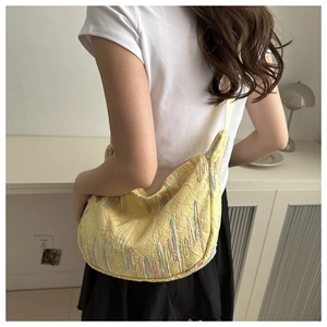 Detail of yellow crescent crossbody bag with embroidery and monogram texture