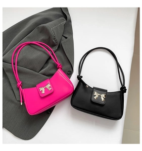 Detail of pink and black leather underarm bags with golden butterfly hardware and knots