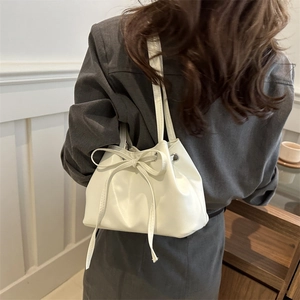 Minimalist white oil wax leather drawstring bucket bag with bow detail on model
