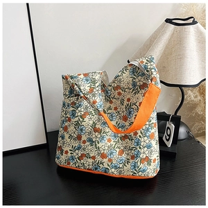 Gros plan du sac cabas vintage fleuri en toile avec bandoulière orange contrastée