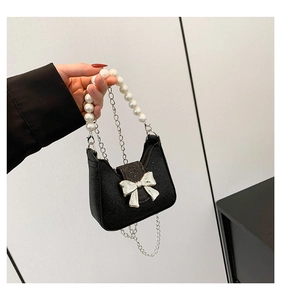 Close-up of black glitter bag with large pearl handle and silver metal bow detail