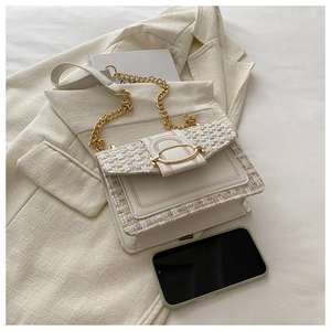 Detail of cream crossbody bag with tweed flap and golden oval buckle closure