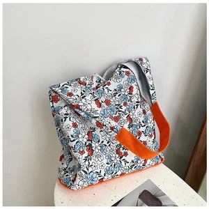 Détail du sac cabas en toile fleurie montrant la bandoulière orange et le fond renforcé
