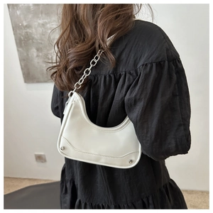 Detail showing white crescent underarm bag with silver thick chain and rivet accents