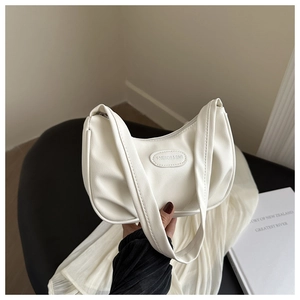 Detailed close-up of ivory cream hobo bag with fashion logo plaque and soft leather texture