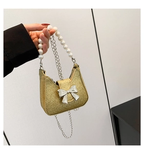 Detail of gold sequin mini bag featuring pearl handle and silver bow decoration